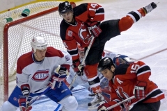 Brian Gionta (14) z New Jersey Devils' přeskakuje Cristobala Hueta z Montreal Canadiens a Michael Komisarek (vlevo) a Jamie Langenbrunner (15) za New Jersey během druhé třetiny středečního zápasu NHL.